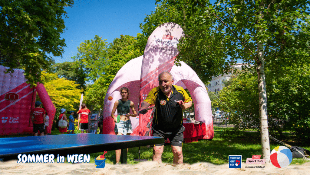 Jung und Alt spielen gemeinsam Tischtennis vor dem Wiener Rathaus und genießen Bewegung, Spaß und Begegnung im sommerlichen Wien.