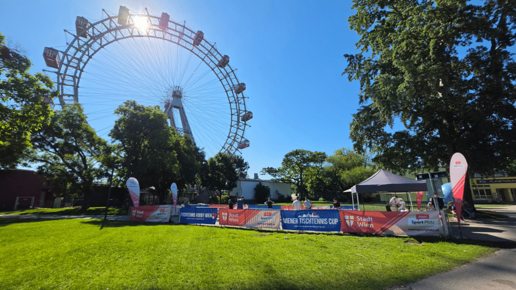 Wiener Tischtennis Cup 2026: Ein gut besuchtes Outdoor-Tischtennis-Event vor der Kulisse des Wiener Riesenrads, bei dem zahlreiche Zuschauer begeistert die Matches an den Platten verfolgen.